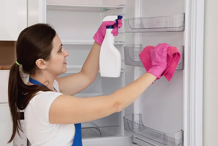 Maid cleaning an empty refrigerator