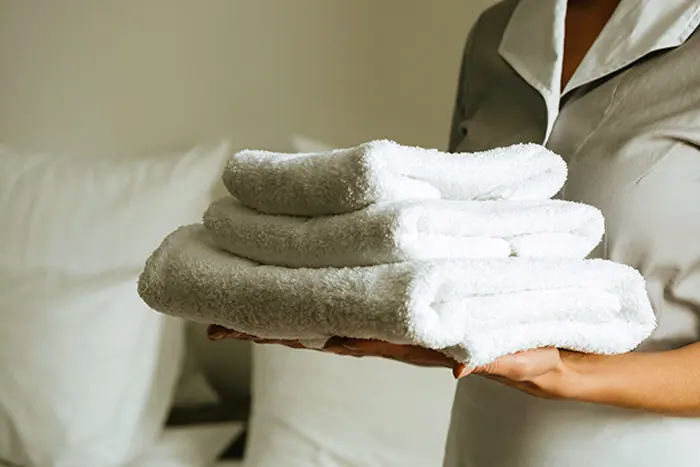 Maid holding replacement towels in a vacation rental