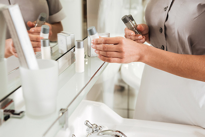 Maid replacing toiletries in bathroom